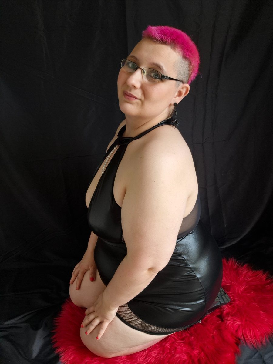 Sandy in einem schwarzen Outfit vor einem schwarzen Hintergrund